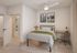 Inviting bedroom with chic decor, featuring a cozy bed with green accents, stylish desk workspace, and en-suite bathroom for convenient living.