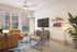 Bright and modern living room featuring a cozy leather sofa, elegant coffee table, chic armchair, and wall-mounted TV. The room boasts natural light from large windows and stylish decor with plants and artwork for a welcoming ambiance.
