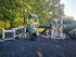 Charming playground surrounded by lush trees, featuring green spiral slides, climbing structures, and a safe play area. Perfect for outdoor family fun.