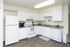 White kitchen with white appliances and wood-style floors at Linden Colonial in Holladay, UT