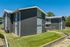 Dark gray two-story building with mature trees at Pines Apartments in Jackson, MS