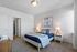 Bright and cozy bedroom with modern decor, featuring a comfortable bed, stylish lamps, and serene artwork on the wall.