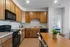 Modern kitchen with sleek wooden cabinets, black appliances, and a spacious dining area adorned with greenery.
