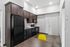 Sleek modern kitchen with dark wood cabinets, black appliances, and a vibrant yellow chair provides a stylish and inviting atmosphere.
