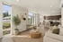 Bright and modern open-plan living area featuring large windows, stylish kitchen with bar seating, and cozy seating arrangements.