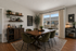 Chic dining area with a wooden table, stylish green chairs, and elegant decor, offering a bright view through large windows.