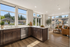 Bright open-plan kitchen and living area with sleek cabinetry, large windows, offering scenic outdoor views.