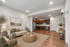 Elegant open-concept living room and kitchen with warm wood flooring and modern stainless steel appliances.