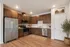 Contemporary kitchen with sleek stainless steel appliances, rich wooden cabinetry, and elegant wood flooring.