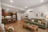 Contemporary open-plan living room and kitchen with sleek plank floors, rich wood cabinetry, and stainless steel appliances.