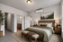 Cozy bedroom with elegant decor, featuring a comfortable bed, soft lighting, and a beautiful nature-themed painting for a tranquil atmosphere.