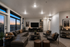 Modern living room with stylish leather furniture, large windows boasting a beautiful city sunset, and elegant decor creating a warm ambiance.