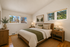 Cozy bedroom with elegant wooden furniture, large windows offering a scenic view, and tasteful decor for a relaxing ambiance.