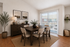 Elegant dining area with wooden table, chic decor, and natural light pouring through large sliding doors, creating a warm and inviting atmosphere.