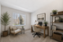 Elegant home office with natural light, featuring a cozy armchair, sleek wooden desk, and modern shelving for a serene workspace.