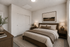 Elegant bedroom with cozy neutral tones, featuring a plush bed, stylish lamps, and serene artwork, perfect for relaxation.