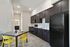 Bright, modern kitchen with sleek dark cabinetry, spacious layout, and vibrant yellow seating.