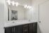 Elegant bathroom with dual sinks, large mirror, and modern lighting, offering a glimpse into a tastefully furnished dining area.