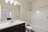 Sleek modern bathroom featuring a pristine white sink, elegant dark cabinetry, and a polished bathtub in a bright and airy setting.