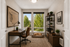 Inviting home office with natural light, featuring a cozy workspace, elegant shelves, and a serene view of lush trees.