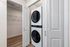 Sleek in-unit laundry area featuring a modern stacked washer and dryer with ample closet storage space.