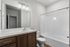 Bright and modern bathroom featuring a sleek vanity, large mirror, and a spacious bathtub with contemporary fixtures.