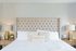 Beautiful queen bed with being and white bedding and quilted headboard.