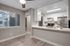 Diningroom with vinyl plank flooring, large window and open view into kitchen with white cabinetry.