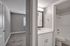 Hallway leading to guest bedroom and bathroom with vanity, and full bathtub with shower.