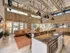 Clubhouse kitchen with grey quartz counter tops, over hang lighting above the bar, and white cabinets. Also featuring our sitting area in distant.