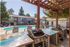 Two BBQ's with bar top under a wooden trellis.