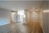 Entrance of apartment showcasing two tone paint and grey vinyl flooring, as well as all white kitchen.