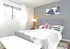 Queen size bed centered  against gray accent wall with a white bench at the foot of the bed.
