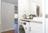 All in one washer dryer combo sits beneath bath room counter along side a whit bath room sink.