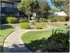 Beachcomber courtyard  with green grass, trees, shrubs, and a circular walkway surrounding a fountain.