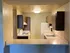 Two Bedroom kitchen with large L shaped counter white appliances and brown cabinetry.