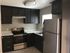 Kitchen featuring stainless steel appliances, white countertops and dark cabinetry.