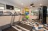 Two treadmills and weigh lifting station with tv and windows along the wall.