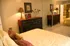 bedroom with large bed, dresser, and mirror door closets