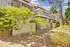 Patios and balconies overlooking a walkway in springtime with groomed landscaping featuring purple flowers, shrubbery, and mature trees.