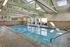 Indoor heated swimming pool with vaulted wood beamed ceiling and one wall made of glass.