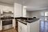 Kitchen sink with gooseneck faucet, stainless steel dishwasher, white cabinetry and generous counterspace.