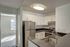 Seascape kitchen with stainless steel stove, a large stainless steel refrigerator, and white cabinetry with black quartz countertops.