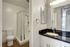 Bathroom vanity with generous black quartz counterspace, white cabinetry, a large mirror mounted above the sink.