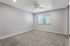 Carpeted bedroom with fan and large window.