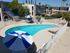 A serene poolside scene at Knollwood Terrace, featuring an outdoor pool with a blue and white umbrella.