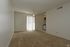 An empty living room at Knollwood Terrace with tan carpet and a ceiling fan.
