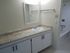A bathroom with a sink and mirror, and white cabinets.