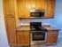 Woodside Apartments kitchen with sleek stainless steel stovetop and microwave, and elegant wood cabinets.