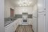 Kitchen with white cabinetry a goose neck faucet and plank flooring.